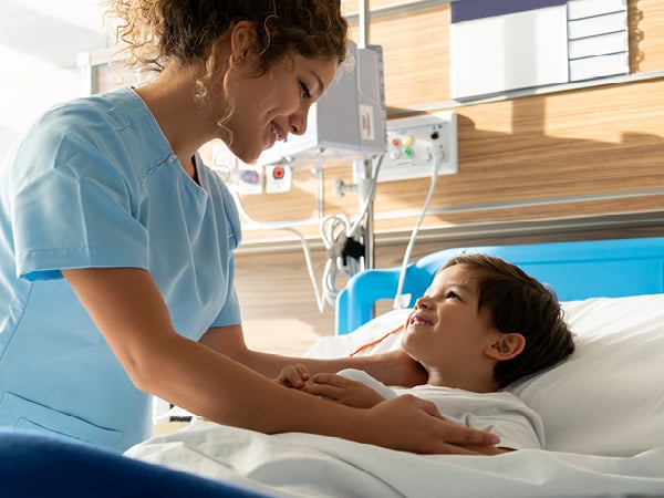 Pflegepersonal kümmert sich um ein Kind in einem Krankenzimmer eines Krankenhauses. 
