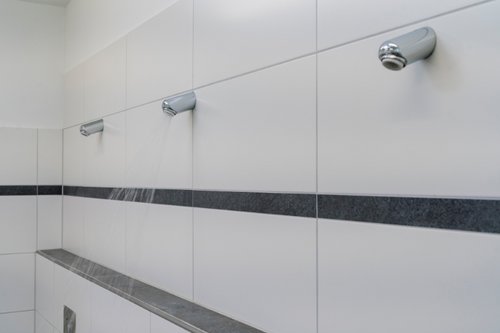 Duschkopf Aerosolarm mit laufendem Wasser in den Duschräumen der Dorfschule Ginderich.