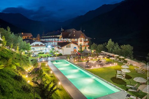 Außenabsicht des Hotels Sonklarhof mit beleuchtetem Infinity-Pool