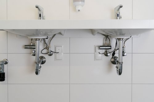 Elektronische Waschtisch-Armaturen XERIS E HD-M auf Waschtischen mit Eckventil-Thermostaten darunter in den Sanitärräumen der Dorfschule Ginderich.