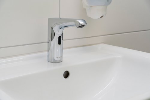 Nahaufnahme einer elektronischen Waschtisch-Armatur XERIS E HD-K in den Sanitärräumen der Dorfschule Ginderich.