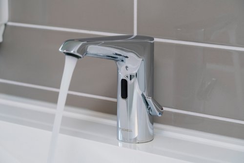 Nahaufnahme einer elektronischen Waschtisch-Armaturen XERIS E HD-M mid. in der Gemeinschaftsgrundschule Wesel mit laufendem Wasser.