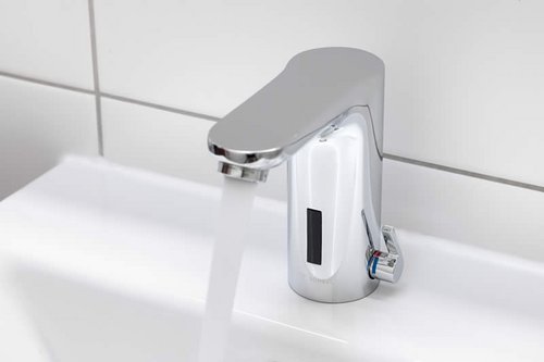 Sicht von schräg oben auf eine elektronische Waschtisch-Armatur CELIS E von SCHELL mit laufendem Wasser in der Kita Spitzholz.