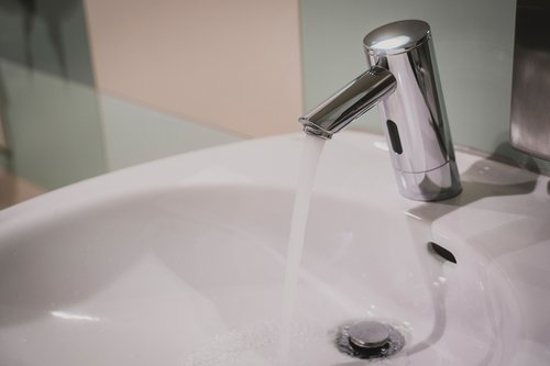 Elektronische Waschtisch-Armatur PURIS E von SCHELL mit austretendem Wasserstrahl